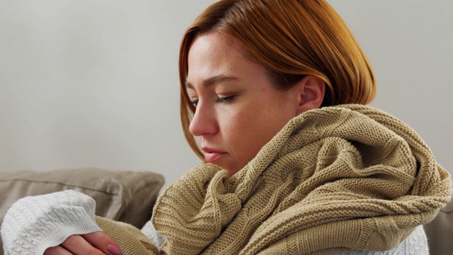 生病的妇女在家里用毯子裹着围巾视频素材