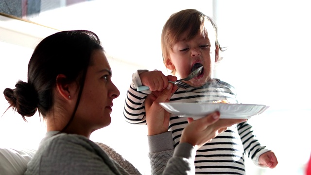 母亲给男婴喂食物。妈妈和婴儿在吃饭视频素材