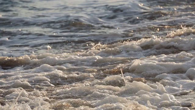 日落时海浪拍打海岸的特写视频素材