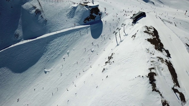 在安道尔的格兰德瓦利拉滑雪胜地沿着滑雪斜坡平稳移动的鸟瞰图。有滑雪者的滑雪缆车。壮丽的雪山和蓝天。冬天的风景。自顶向下的观点。视频素材