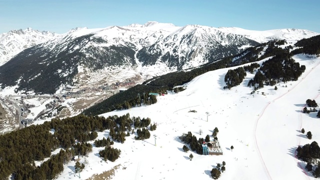 在安道尔的格兰德瓦利拉滑雪胜地沿着滑雪斜坡平稳移动的鸟瞰图。壮丽的雪山和蓝天。冬天的风景视频素材