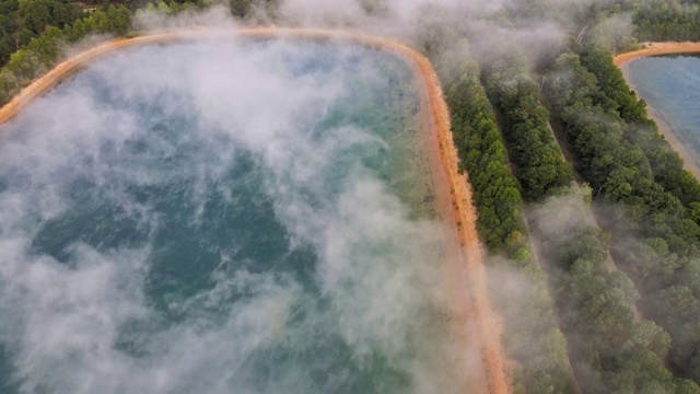 鸟瞰图的晨雾雾景观，湖泊在秋天森林雾气模糊的背景视频素材