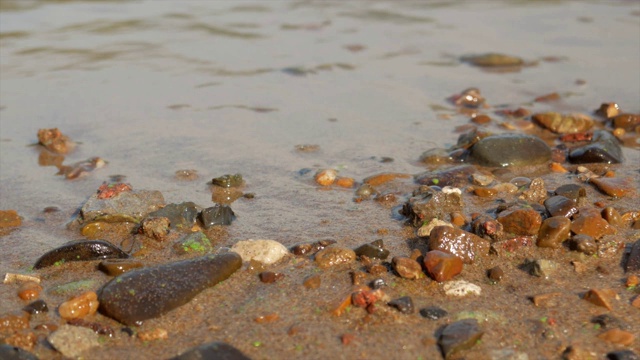 小波浪带着小卵石冲过沙滩，特写视频素材