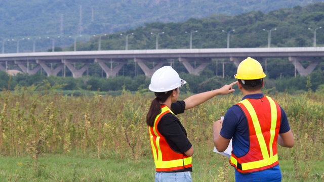 建筑师和工程师正在现场检查公路施工图纸，在施工现场讨论工作，专业工程师检查工作。视频素材