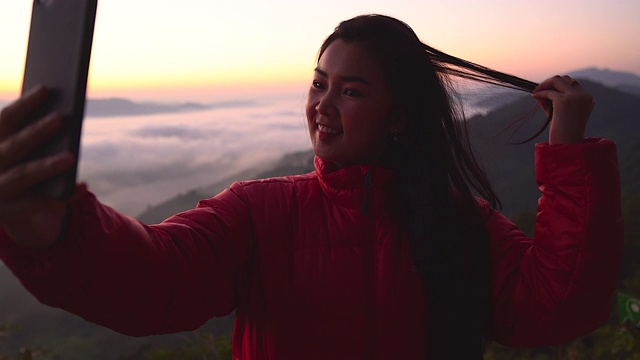 在有阳光和雾的山上拍摄风景的年轻女子的剪影。带着相机独自旅行的背包客。假日旅游和度假概念。视频素材