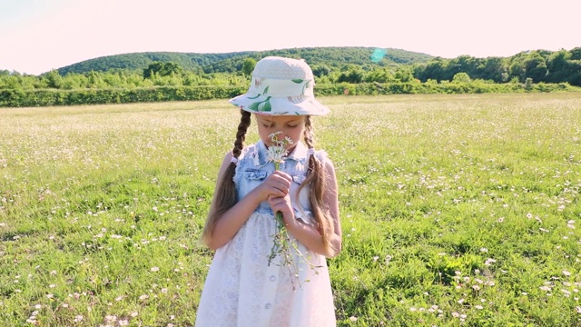 阳光明媚的夏天。漂亮的小女孩穿着裙子，手里拿着一束雏菊。孩子和野花。视频素材