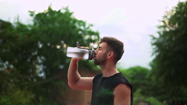 肖像的运动男子饮用矿泉水后，户外锻炼视频素材