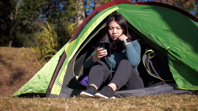 一名妇女在森林里的帐篷营地使用手机视频素材