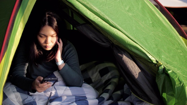 一名妇女在森林里的帐篷营地使用手机视频素材