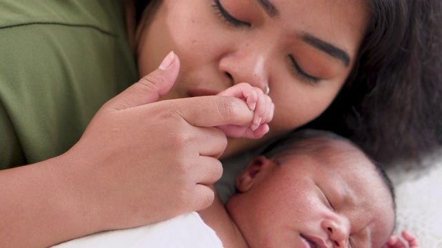 妈妈深情地吻着新生婴儿的手。视频素材