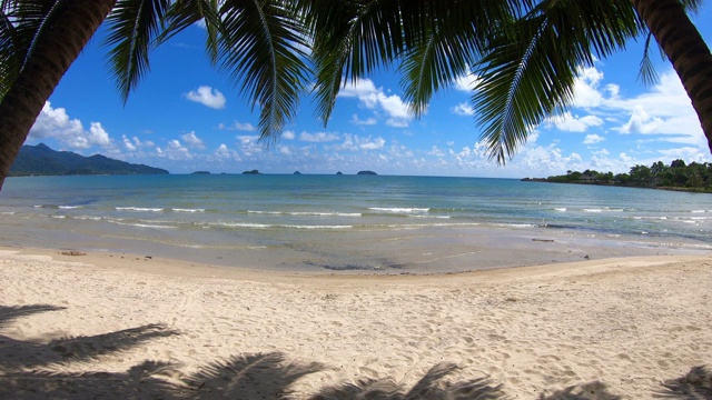 清澈的大海和白色的沙滩，椰子树和天空为背景，在泰国特拉特Koh Chang。视频素材