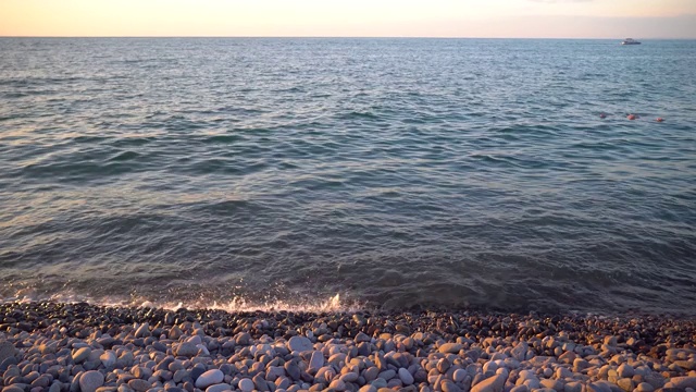 海面上，五彩缤纷的夕阳载着帆船，人在他的背上游泳视频素材