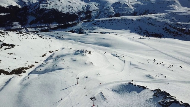 在安道尔的格兰德瓦利拉滑雪胜地沿着滑雪斜坡平稳移动的鸟瞰图。冬天的风景。山上餐厅的顶视图和滑雪缆车的长队视频素材