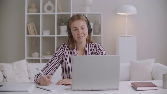 年轻的女性人力资源经理正在通过电脑视频聊天面试，通过网络面试，在抄写本上做笔记，远程沟通视频素材