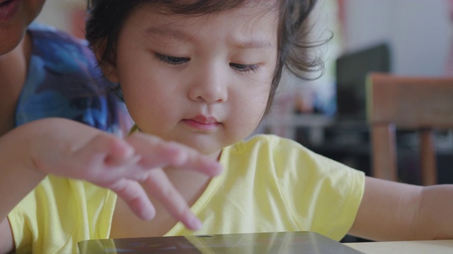 手持POV拍摄奶奶和孙子在家客厅看数字平板电脑。快乐的爷爷和孙女一起看电子屏幕，在家里放松。可爱的小女孩用手指触摸屏幕。视频素材