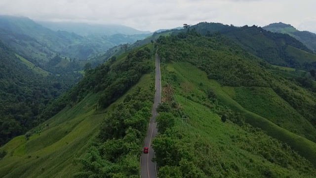 鸟瞰图森林道路在秋天与汽车。红色的汽车在柏油路上行驶，穿过广阔的森林视频下载