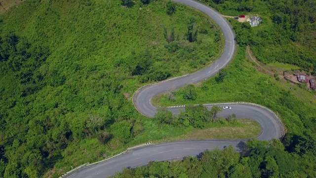 鸟瞰图森林道路在秋天与汽车。红色的汽车在柏油路上行驶，穿过广阔的森林视频下载