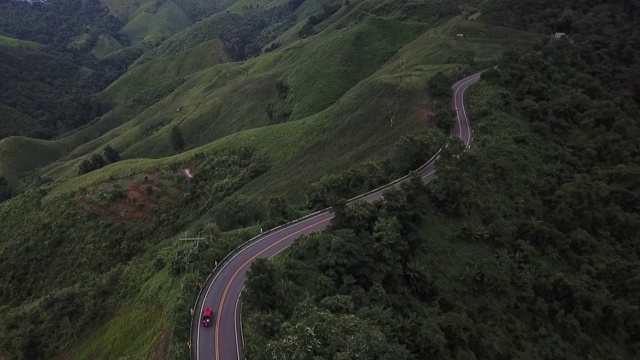 鸟瞰图森林道路在秋天与汽车。红色的汽车在柏油路上行驶，穿过广阔的森林视频下载