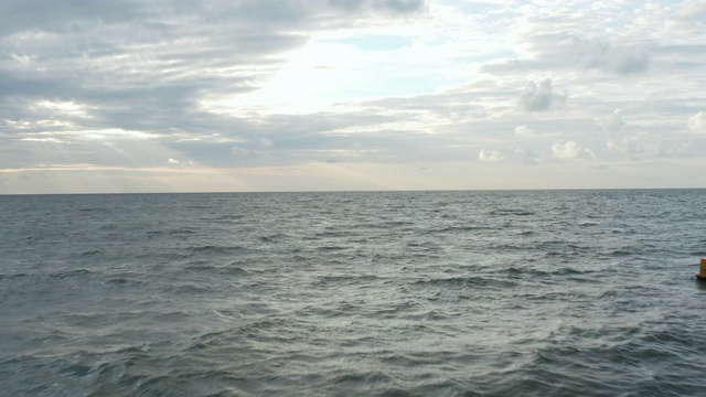 波涛汹涌的海面上的黄色浮标与远处的日落云景，空中向前视频素材