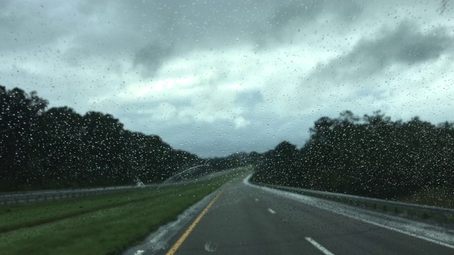 在空旷的高速公路上驾驶POV，最初关注的是挡风玻璃上的雨滴视频素材