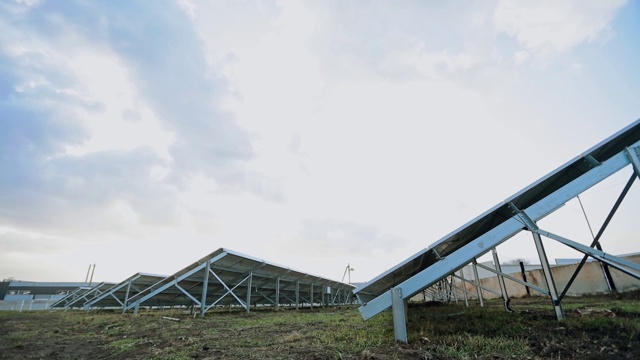 创新的太阳能农场。地上有太阳能电池的金属建筑。光伏太阳能板产生替代能源。视图从下面。视频素材