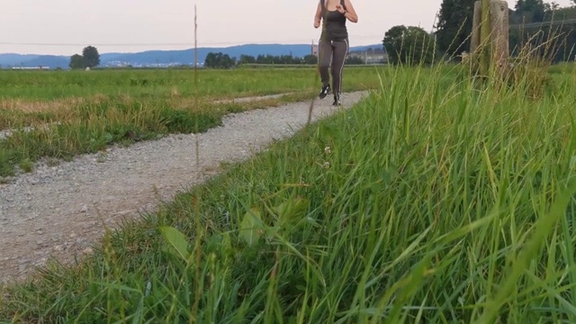 一个小女孩沿着一条碎石小路跑过田野。视频素材