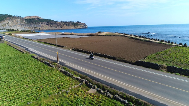 韩国济州岛西浦西沿海公路上的摩托车驾驶视频素材