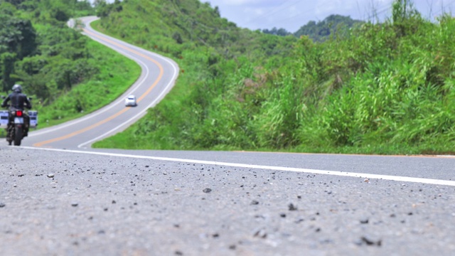 场景散焦的男子驾驶一辆摩托车在道路上翻山越岭在泰国北部视频素材