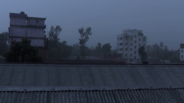 在户外用我的相机拍雨。雨点落在城市平地和树木背景的锡屋顶上。雨在多云的天空与移动的树木在空中。夏季雨季有大雨。视频素材