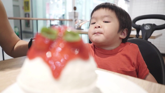 亚洲小男孩和妈妈在冰淇淋店吃冰酥视频素材