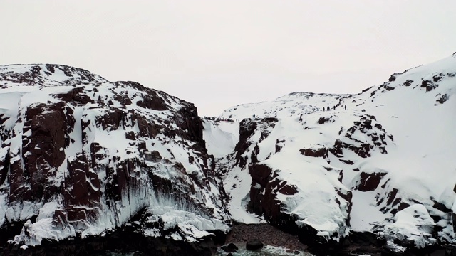 鸟瞰图挪威和雪海附近的海岸在冬季，欧洲。镜头。白雪皑皑的山峦，白雪覆盖的岩石和平静冰冷的大海的自然景观视频素材