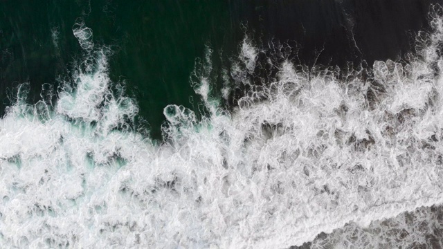 翠绿色的海浪从上面冲上岩石海岸视频素材