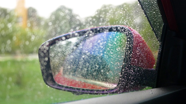 在细雨中，汽车侧镜和湿车窗的视野不稳定，在道路上行驶时，雨滴的水滴反射模糊。视频素材