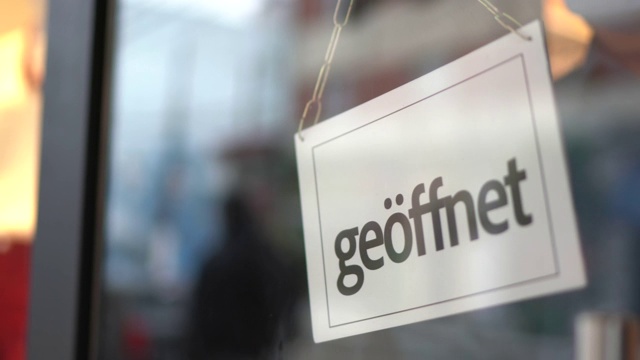 店主转过身来打开店门上的标识(geöffnet)视频素材