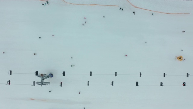 在安道尔的格兰德瓦利拉滑雪胜地沿着滑雪斜坡平稳移动的鸟瞰图。有滑雪者的滑雪缆车。壮丽的雪山和蓝天。冬天的风景。视频素材