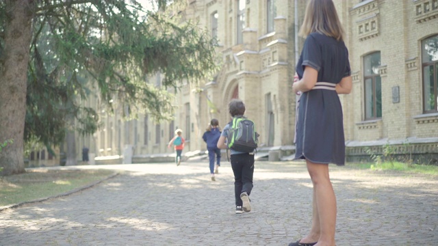 教师在中学生入学前向他们的手上喷洒消毒剂。戴口罩的白种妇女控制学童Covid-19消毒。冠状病毒的教育概念。视频素材