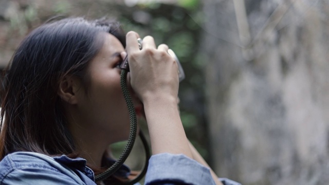 肖像美丽的潮女人使用胶片相机拍摄照片复古建筑设计在泰国曼谷的一条小街道。视频素材