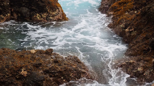 蓝绿色的海浪撞击着海岸附近的火山岩。视频素材