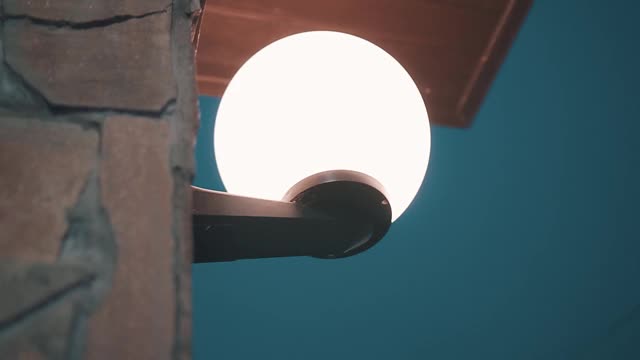 一个漂亮的圆灯笼挂在房子的墙上，照亮周围的空间。摄像机是动态拍摄的视频素材