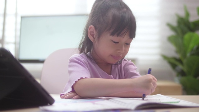 亚洲女儿在家里用数字平板电脑学习在线课程视频素材