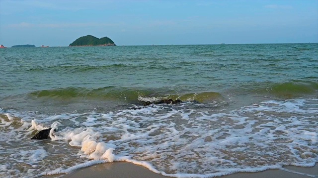 海浪撞击岩石，缓慢的运动与岛屿背景和美丽的沙滩。视频素材