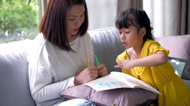 妈妈在家里的客厅教小女孩画画视频素材