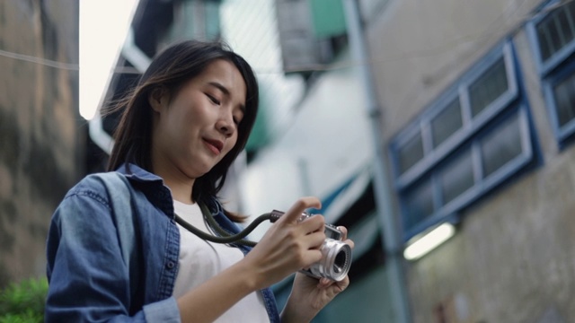 亚洲女性旅行者在泰国曼谷的一条小街上用胶卷相机拍照。视频素材