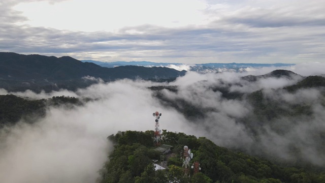 鸟瞰图，美丽的全景景观，日出在山顶与雾和温暖的光在信号中继站杆子日出，通信技术概念。湄慕兰邦，泰国。视频素材