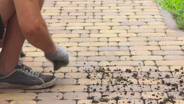 人们清理铺路板之间的缝隙，清除苔藓和灰尘视频下载