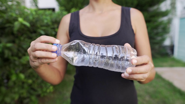 一个女人在自家后院打碎一个塑料瓶的臀部水平镜头视频素材