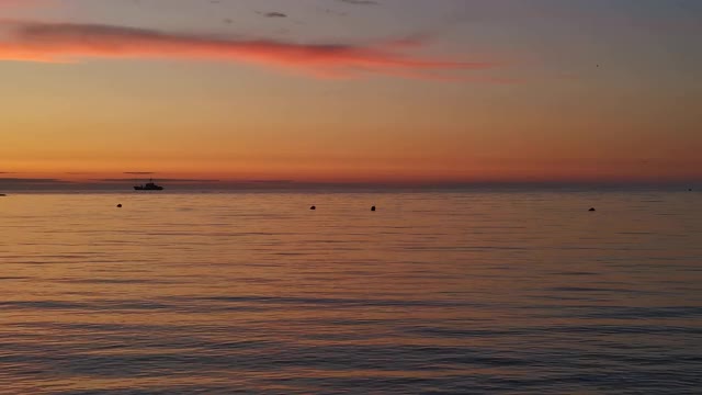 海面上橙色的夕阳，地平线上有一艘船。宁静祥和的夜景。视频素材