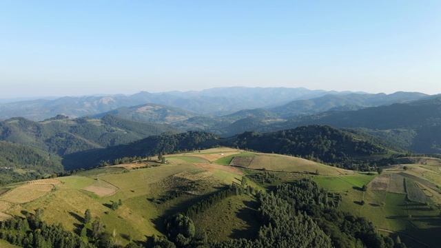 在阳光明媚的夏日或春日，塞尔维亚科帕onik山附近的Brzece村，无人机在山上拍摄田野和树林视频素材