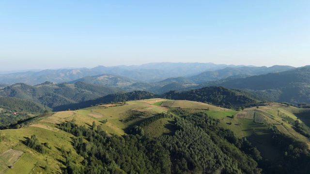 在阳光明媚的夏日或春日，塞尔维亚科帕onik山附近的Brzece村，无人机在山上拍摄田野和树林视频素材