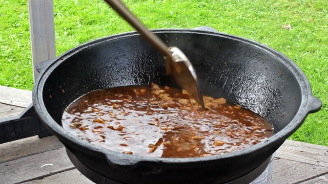 烹饪真正的乌兹别克肉饭，厨师用铁勺在火上炖肉视频素材